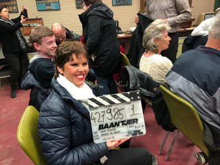 Deelneemster houdt een klapbord vast op de set