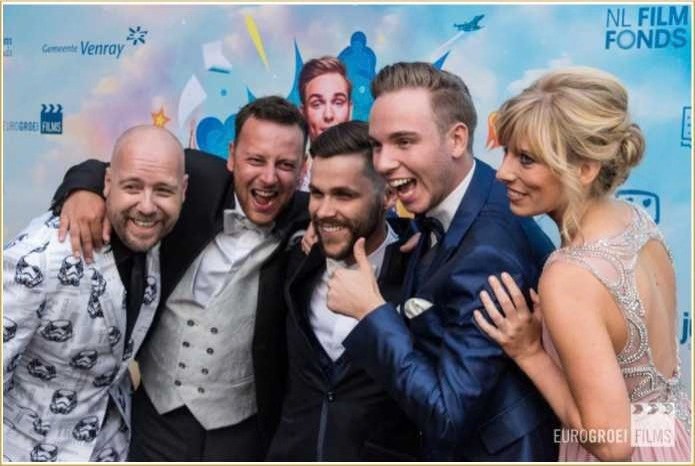 Gasten poseren vrolijk voor de achterwand van een première